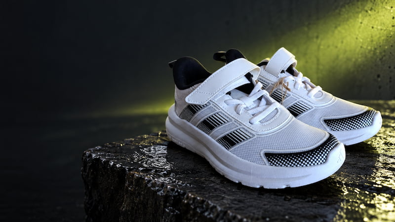 Première mise en scène publicitaire de la paire de chaussures sur un socle sombre, avant suppression du cordon et redressement de la languette.